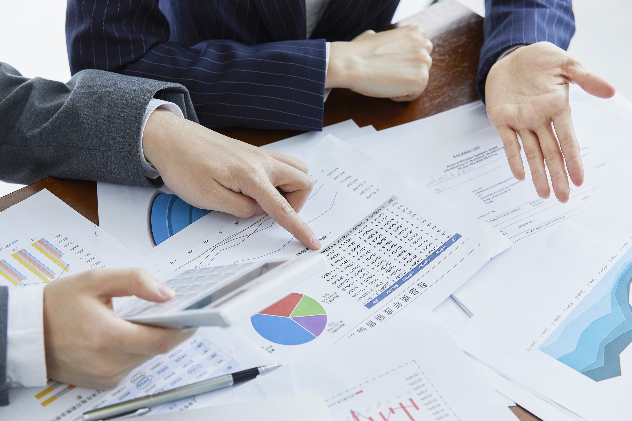 Two businessmen in elegant suits at a business meeting making calculations in the office